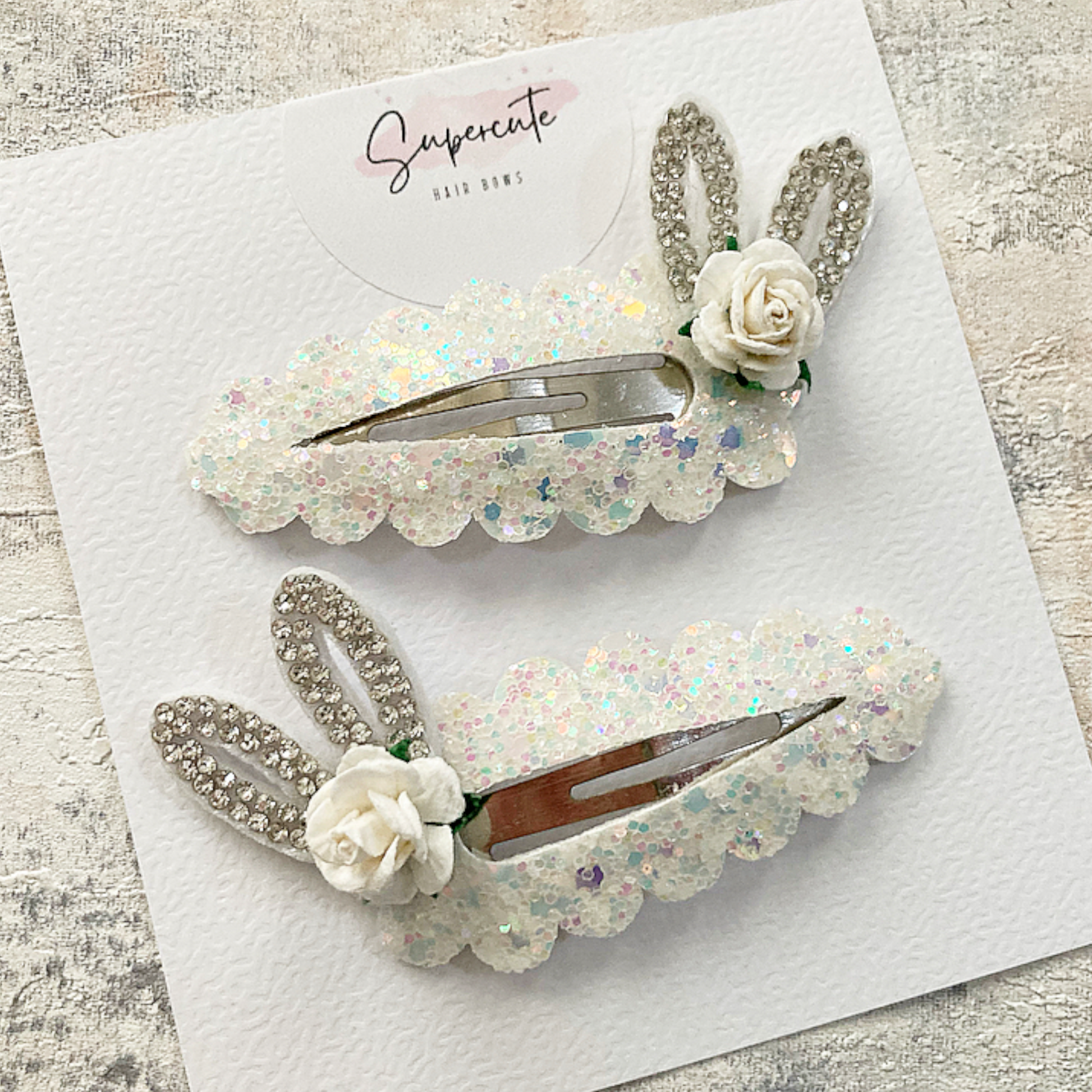 Sparkly bunny ear hair clips In a white glitter effect with diamanté ears and a small white rose 